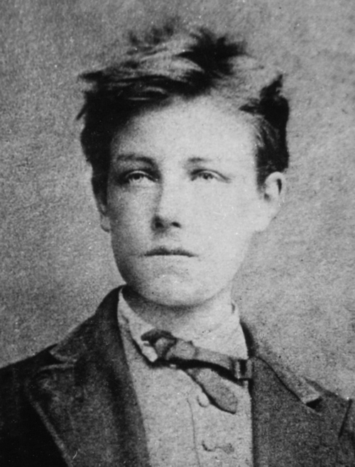 Portrait noir et blanc d'un jeune homme avec des cheveux en désordre, portant un costume et une cravate, regard sérieux.